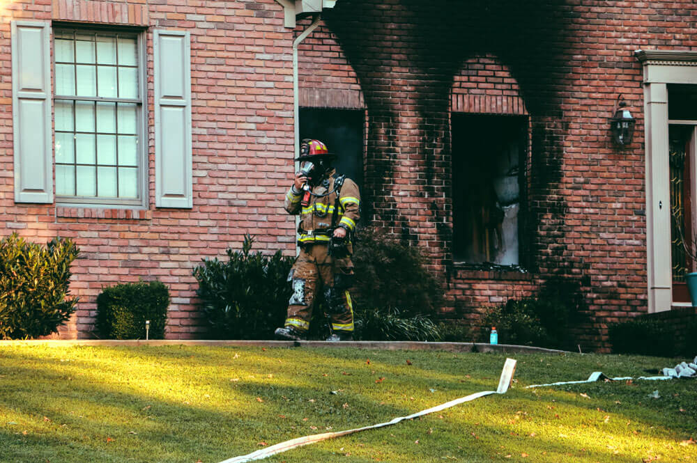 Fireman walking in front of house that caught on fire