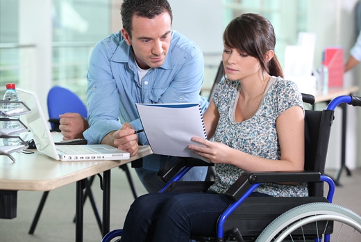 woman in wheelchair reviewing paperwork with man