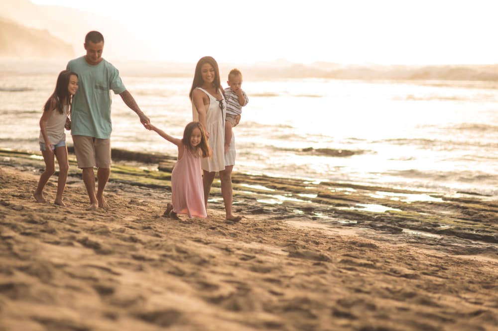 Mom And Dad Walk Along The Beach With Three Children