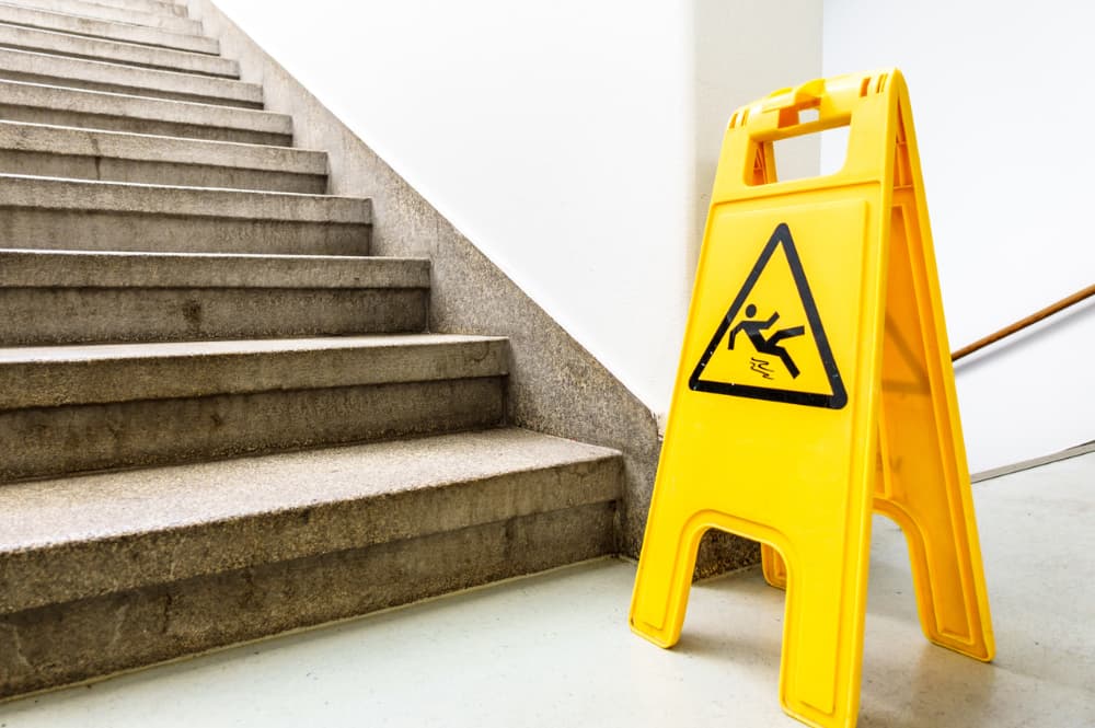A caution sign on a wet floor near a stairway