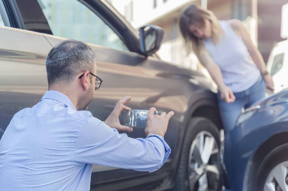A man taking a photo of a car crash on a cell phone