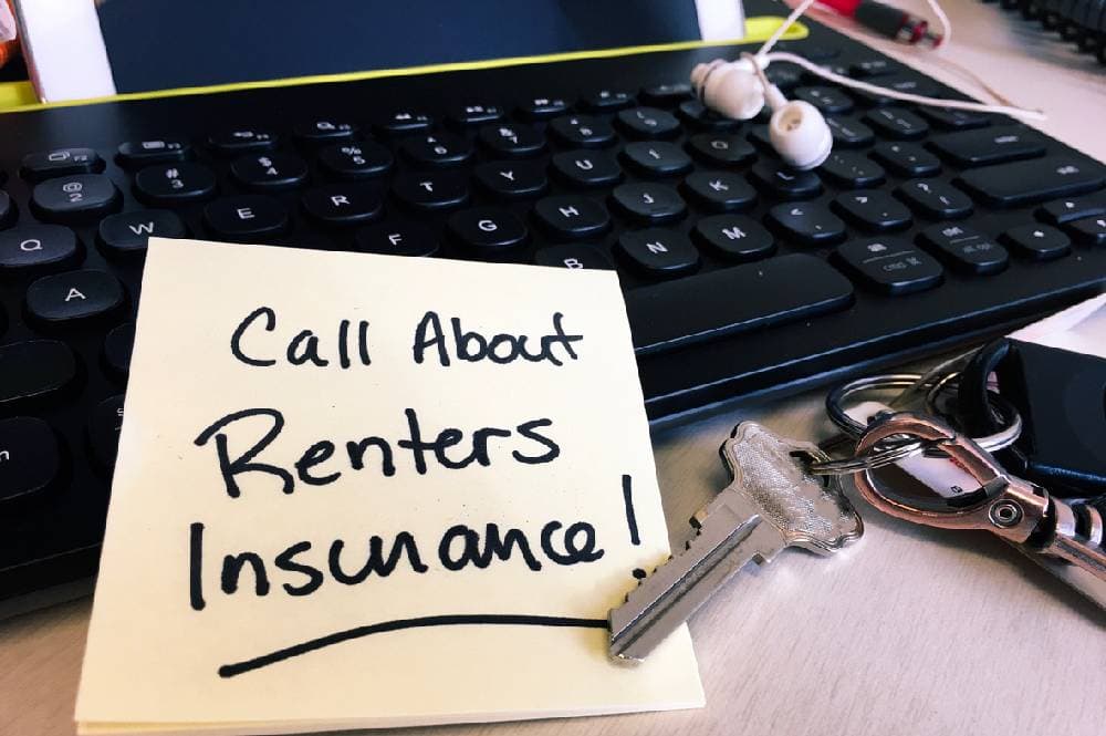 Sticky note with ‘call about renters’ insurance!’ written on it, set on computer keyboard with keys next to it