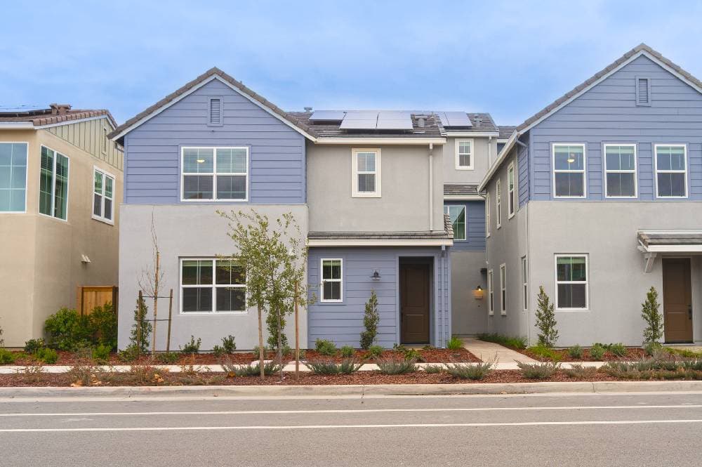 Newly built condominiums with blue siding and landscaping
