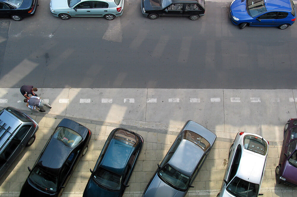 Cars parked in a lot and on the street parked cars.