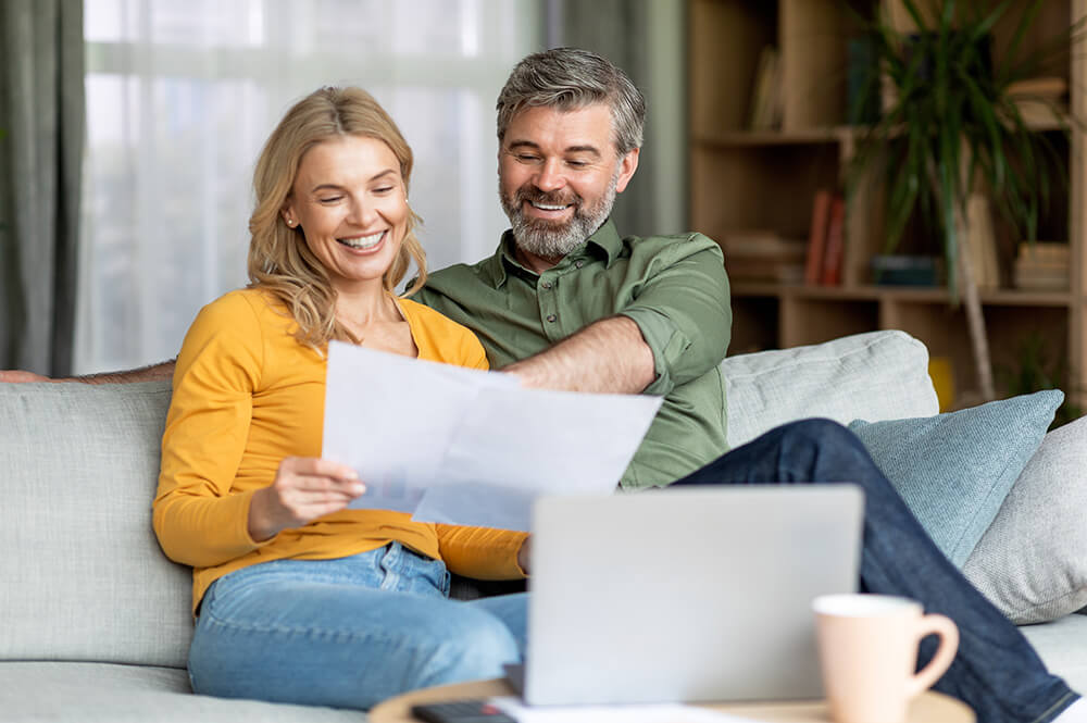 Couple looking over papers while sitting on the couch.
