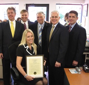 Erika Muller receiving an award. Sitting in front of other men.