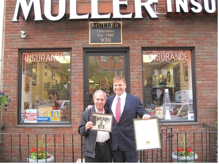 Roger Muller, Jr. standing in front of the Muller Insurance office building.