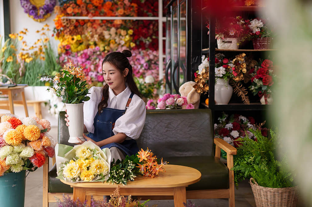 Woman in florist shop holding a vase of flowers.